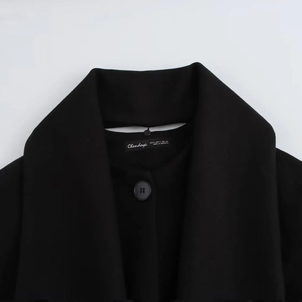 Women's long black polyester overcoat with a gray artificial fur collar, showing street fashion style and front pockets.