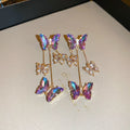 Blue purple butterfly earrings with crystal flowers and tassel details on silver needle posts