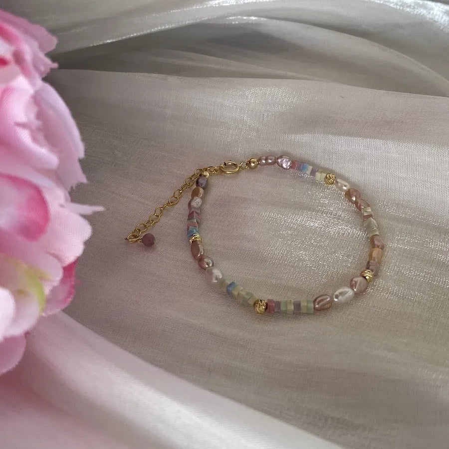 Close-up of a women's mini bracelet with irregular natural pearls set in 14K gilded purple silver, shown with its matching necklace.