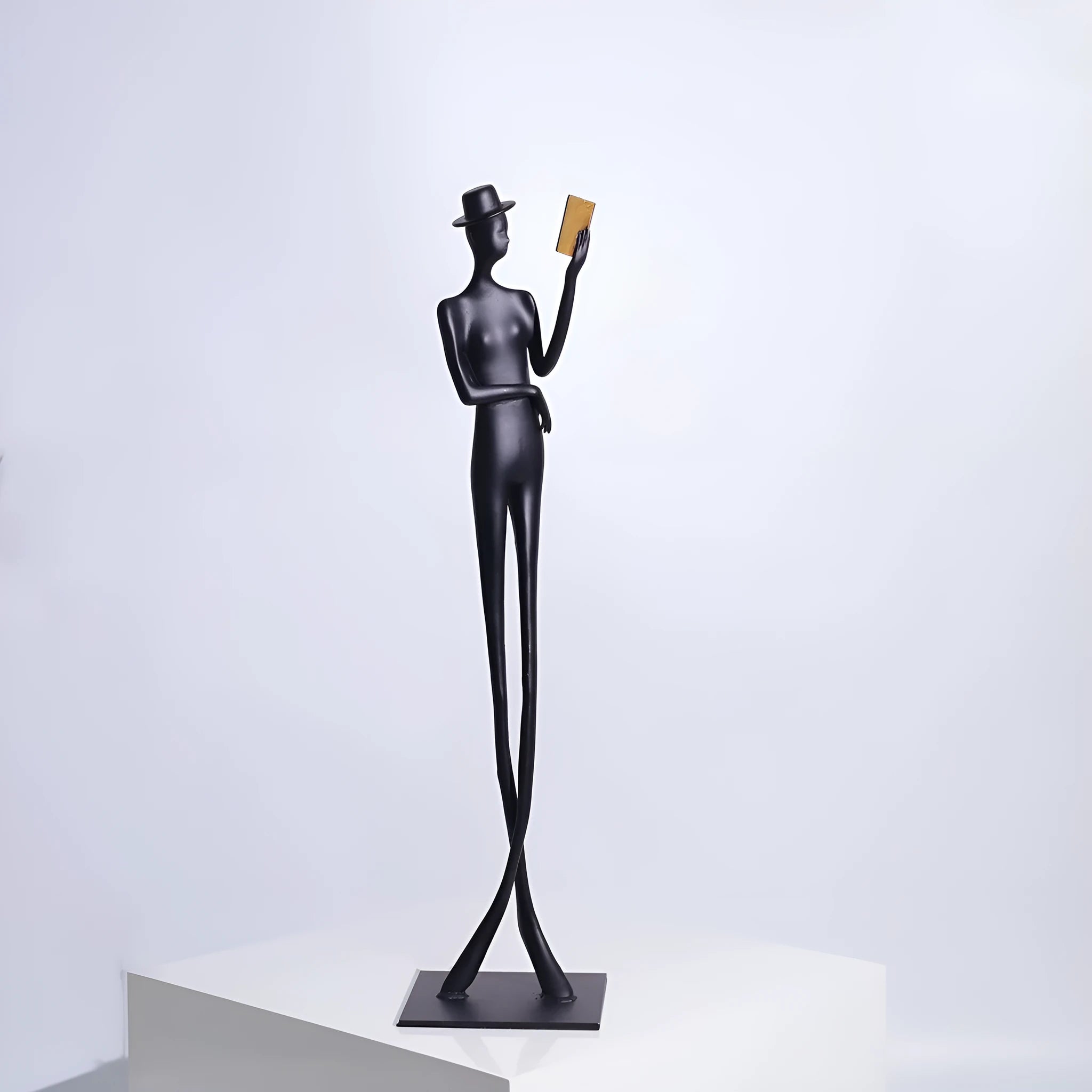Black aluminium desktop sculpture of reading woman figure measuring 12x12x51cm