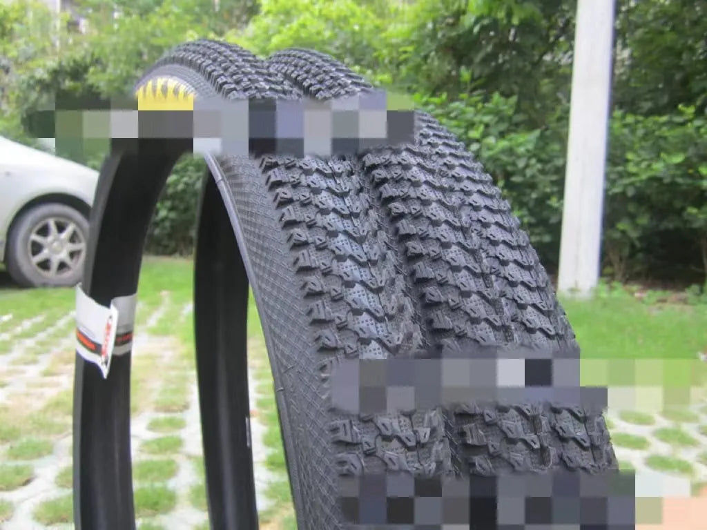 Ultralight black mountain bike tyre with white label sidewall option on a trail.