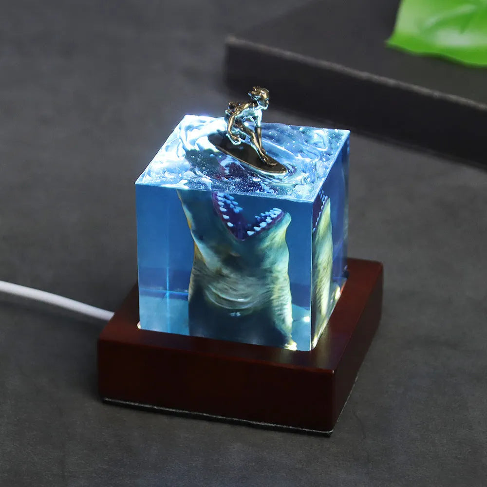 Epoxy resin shark surf scene night light ornament in 5cm and 8cm sizes on a table.