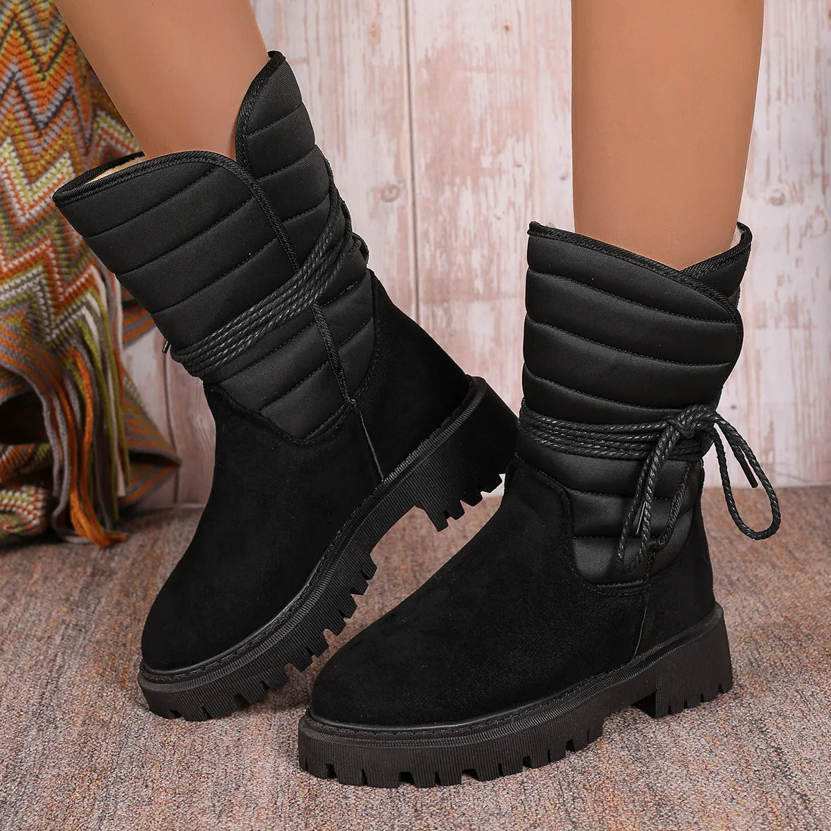 Women's black suede snow boots with chunky heel and lace-up design showing fleece lining