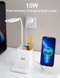 Modern black and white desk lamp with wireless charging pad, pen holder, and storage compartment.