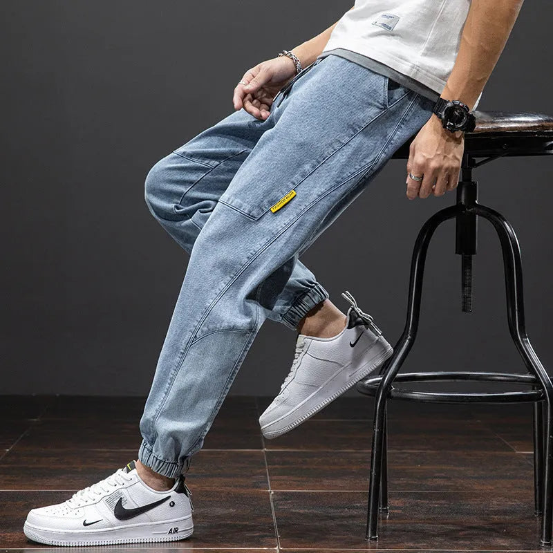 Men's loose fit blue cargo jeans with straight leg and cargo pockets on a plain background.