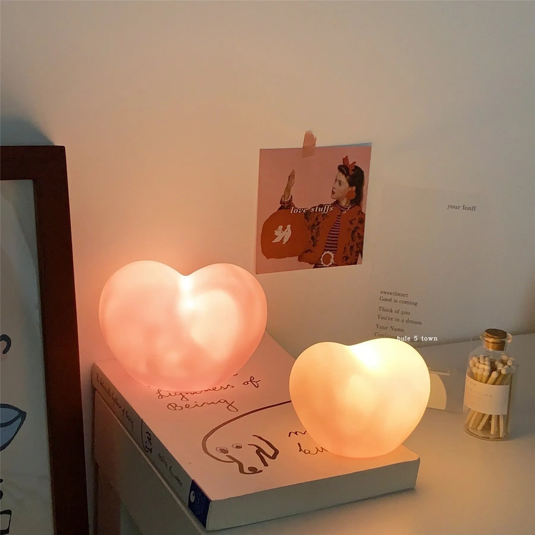 White and pink vinyl trumpet-shaped atmosphere lamps glowing with warm light on a dark surface.