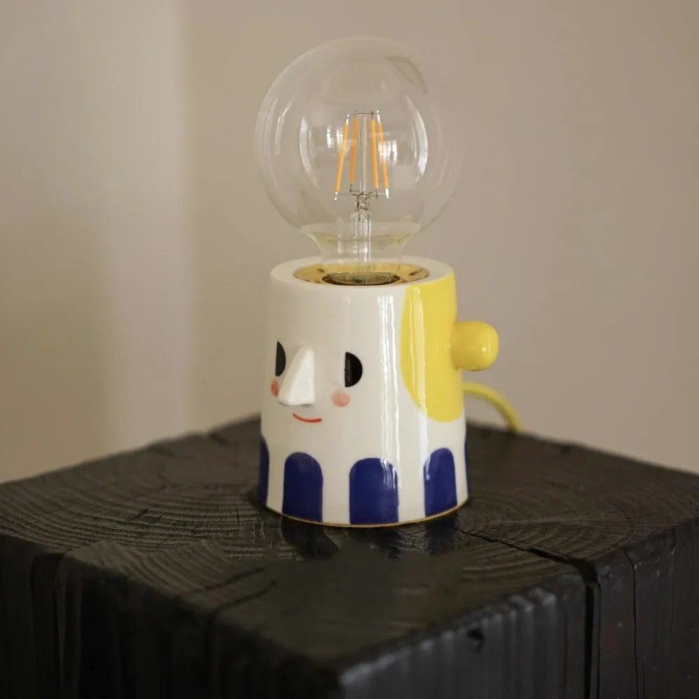 Handmade ceramic bedside lamp with ball-shaped headlight design on wooden surface