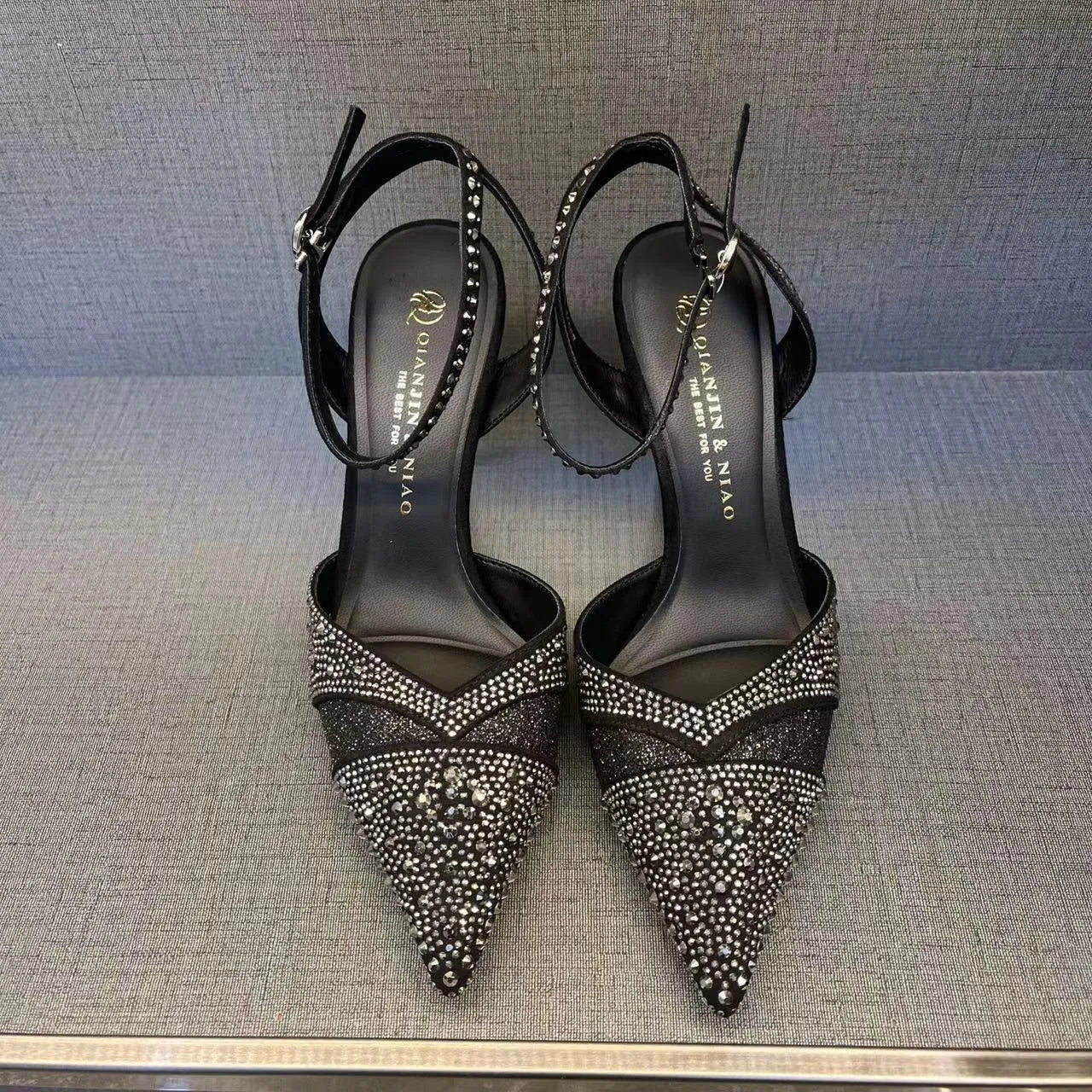 Black women's hollow high heels with pointed toe, stiletto heel, and red sole on a plain background.
