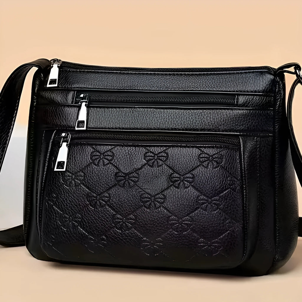 Black women's crossbody messenger bag with embossed texture and shoulder strap