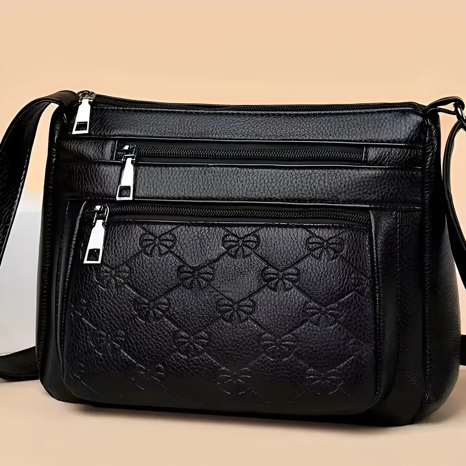 Black women's crossbody messenger bag with embossed texture and shoulder strap