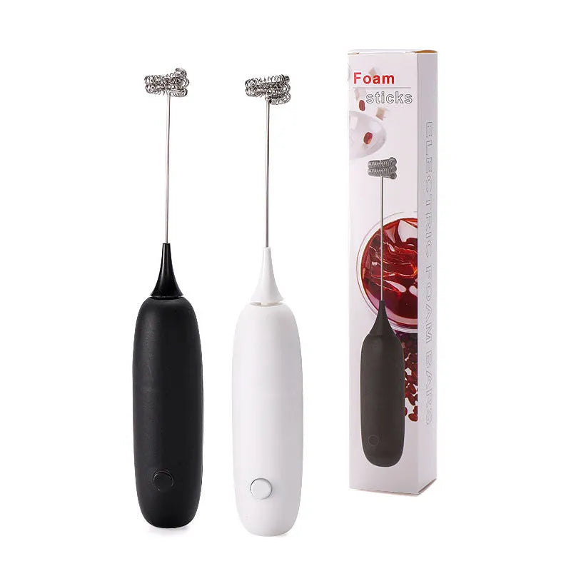 A black and a white hand-held electric milk frother for coffee, displayed on a kitchen counter.