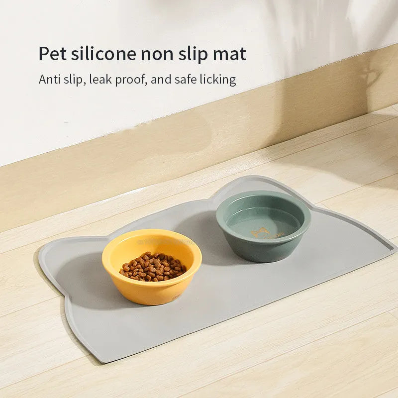Blue silicone pet feeding mat with cat head design under food and water bowls