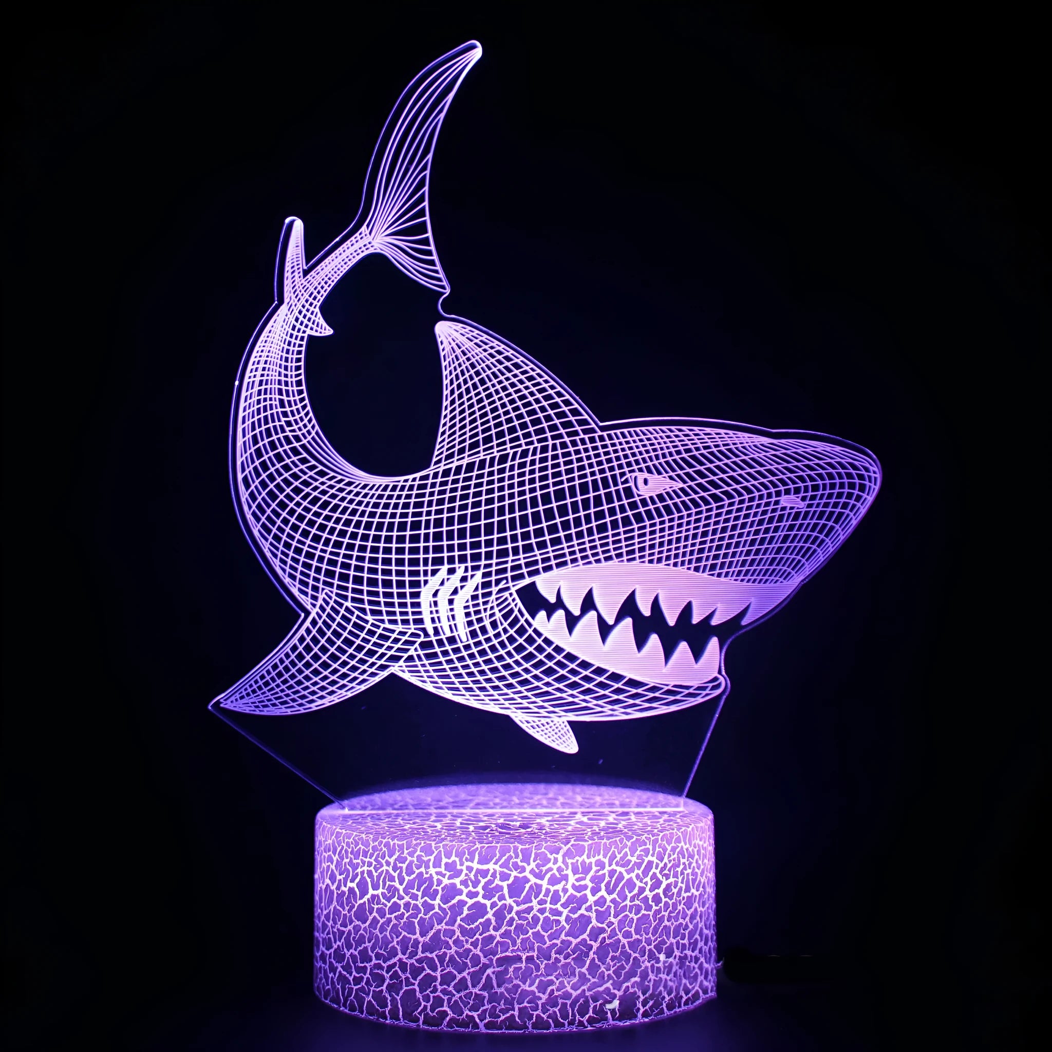 Shark-shaped 3D LED table lamp on a table showing multi-colour light effect from acrylic panel.