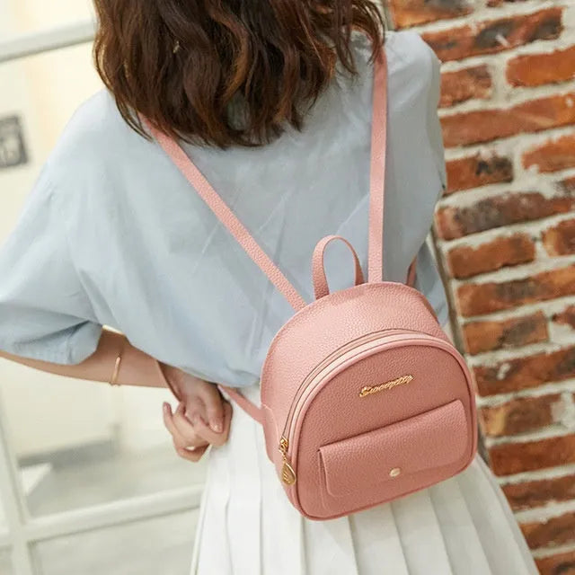 Small black women's PU backpack purse with a zipper, shown with a mobile phone for scale.