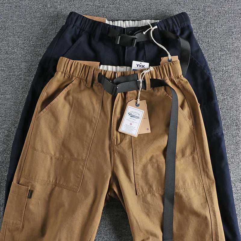 Men's khaki and dark blue cotton work trousers with mid waist and zipper fly on a size chart