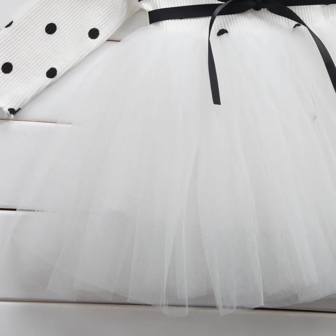 Baby girl wearing a long sleeve black tutu dress with lace detail, suitable for a party or casual wear.