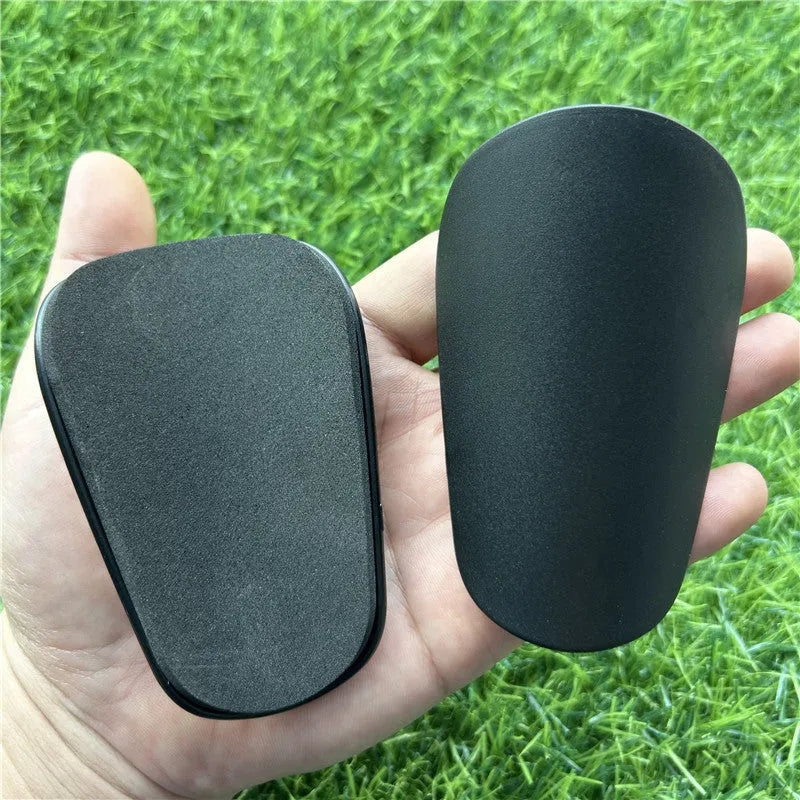 Extra small plastic football shin guards measuring 8x5cm in black and white for youth players