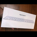 White Apple Bluetooth G6 wireless keyboard with multimedia keys in a metal box.
