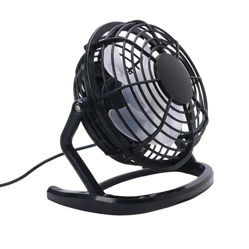 Compact black USB desk fan with adjustable tilt angle on a wooden desk next to a laptop