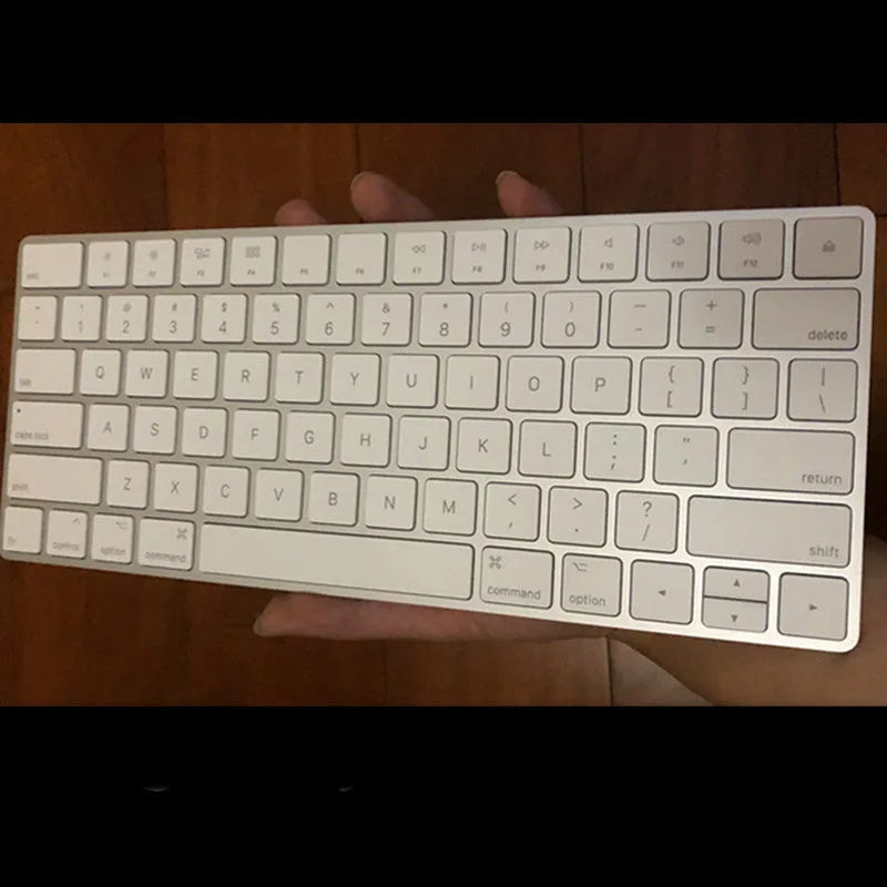 White Apple Bluetooth G6 wireless keyboard with multimedia keys in a metal box.