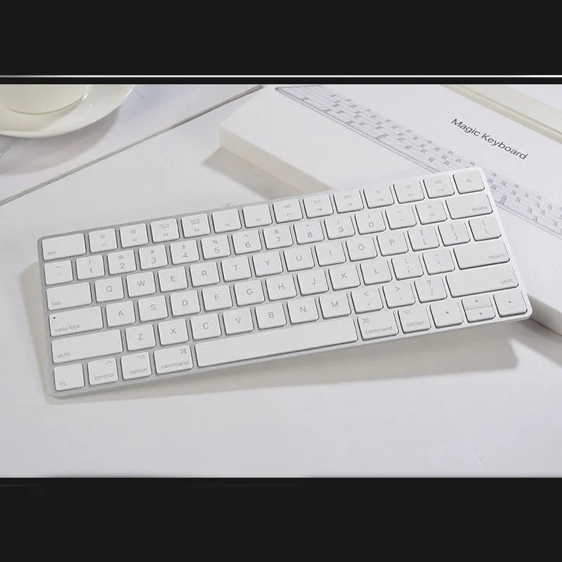White Apple Bluetooth G6 wireless keyboard with multimedia keys in a metal box.
