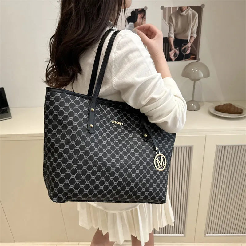 Women's black PU leather shoulder bag with sewing thread detail on a table.