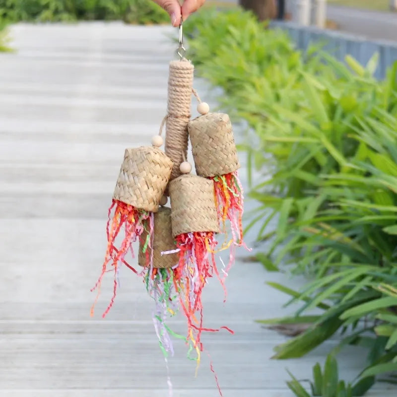Wood and sisal rope parrot toy with colourful shredded paper hanging inside a bird cage.