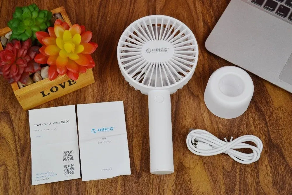 White ORICO FH1 portable USB desk and handheld fan with rechargeable battery on a wooden table.