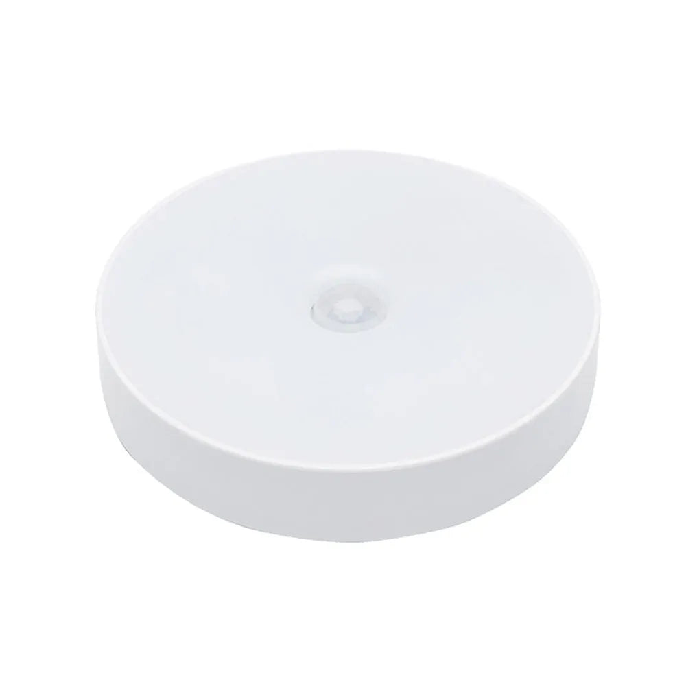 Small white circular USB rechargeable LED motion sensing night light with adhesive backing.