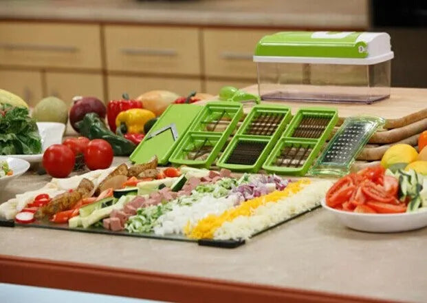 Green manual food chopper with stainless steel blades and plastic body on a kitchen worktop.