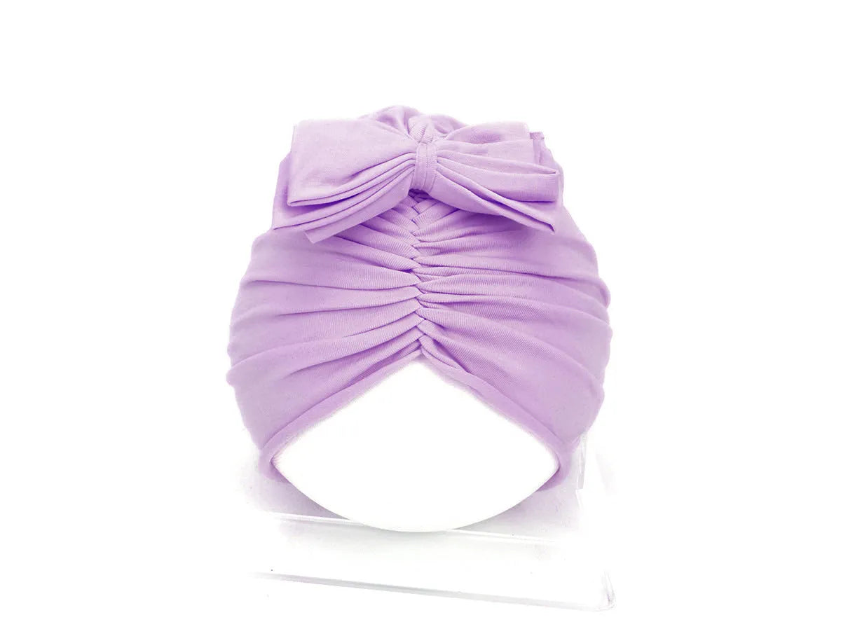 Soft acrylic knitted baby girl turban hat in a solid colour, shown on an infant