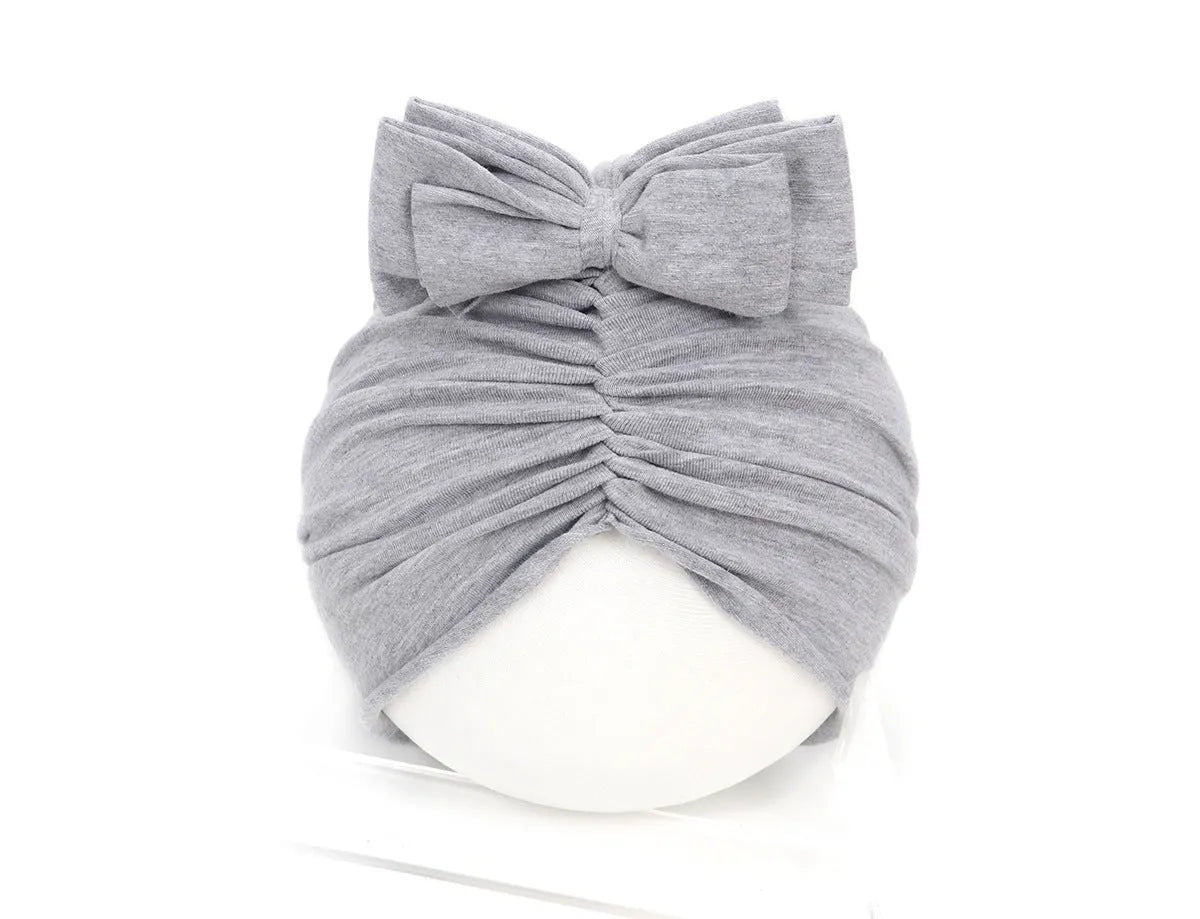 Soft acrylic knitted baby girl turban hat in a solid colour, shown on an infant