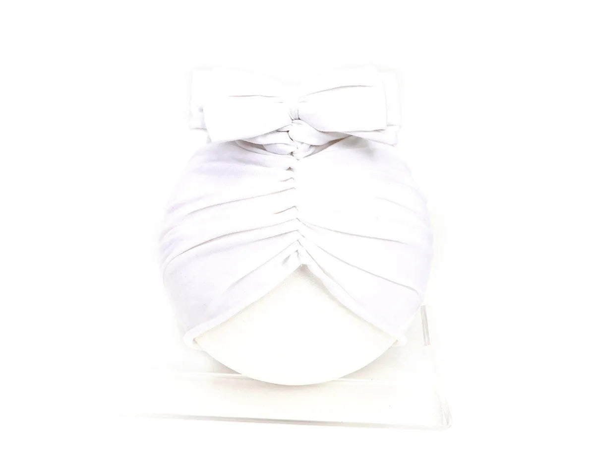 Soft acrylic knitted baby girl turban hat in a solid colour, shown on an infant