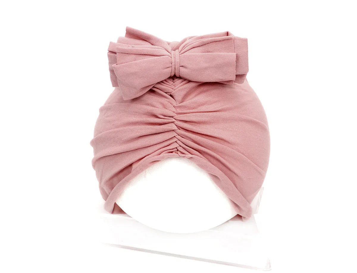 Soft acrylic knitted baby girl turban hat in a solid colour, shown on an infant