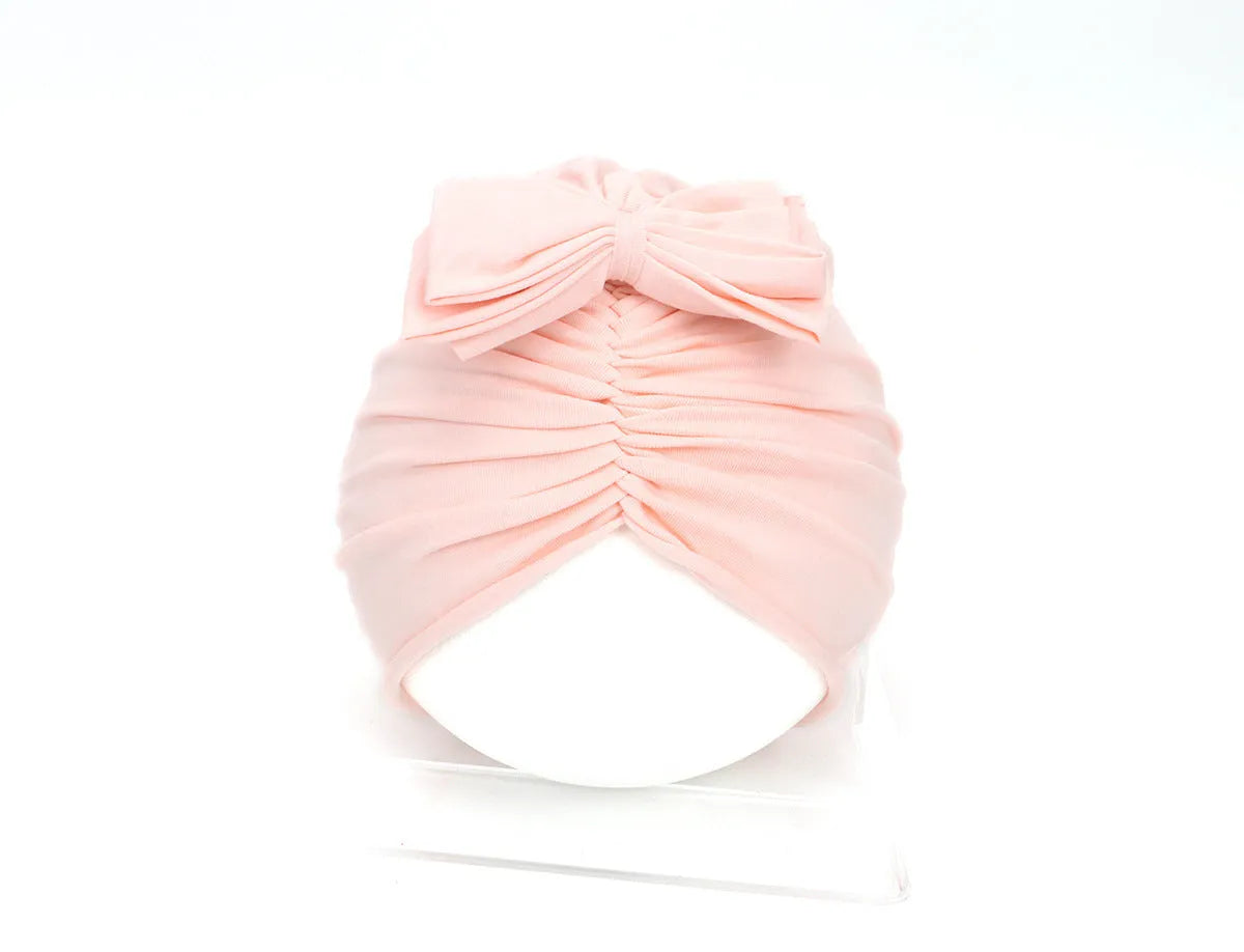 Soft acrylic knitted baby girl turban hat in a solid colour, shown on an infant
