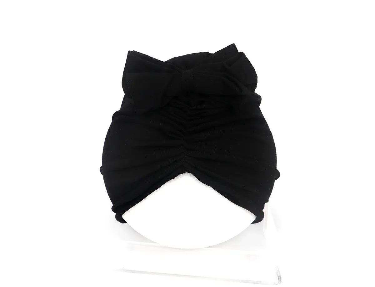 Soft acrylic knitted baby girl turban hat in a solid colour, shown on an infant