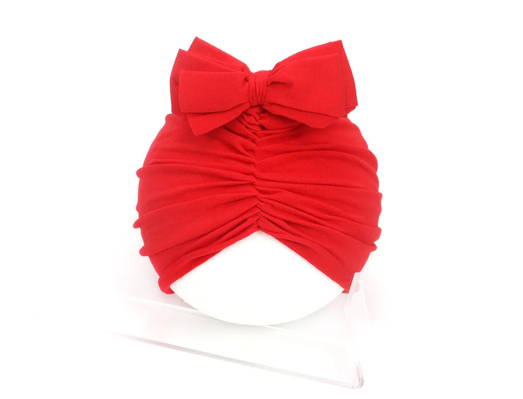 Soft acrylic knitted baby girl turban hat in a solid colour, shown on an infant