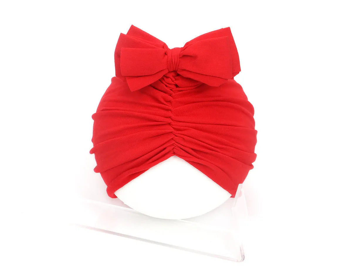 Soft acrylic knitted baby girl turban hat in a solid colour, shown on an infant