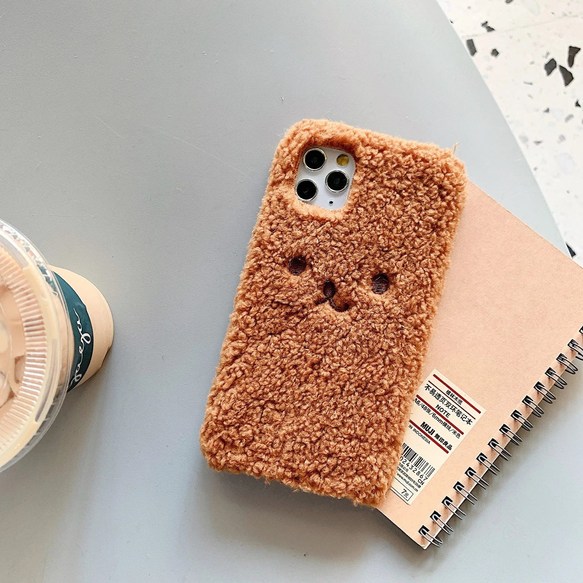 Brown embroidered plush cartoon bear face on a soft TPU iPhone phone case.
