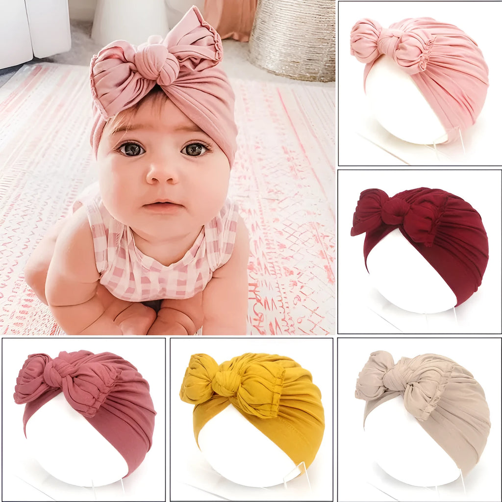 Soft acrylic knitted baby girl turban hat in a solid colour, shown on an infant
