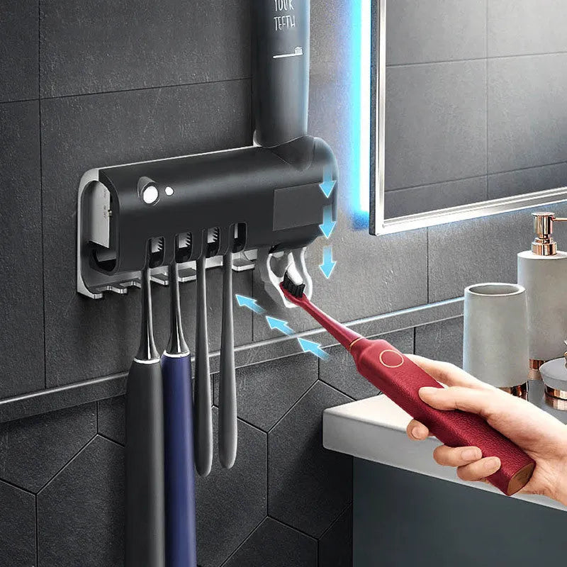 Black and white intelligent UV toothbrush steriliser with automatic toothpaste squeezer mounted on a bathroom wall.