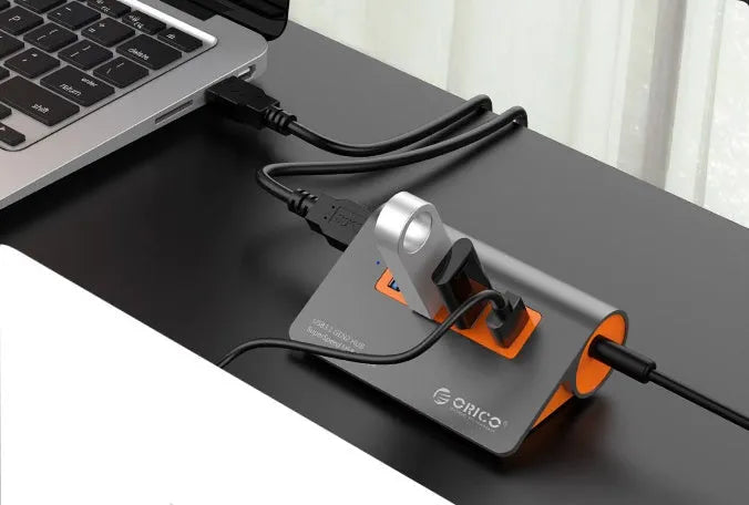 Dark grey and orange aluminium USB-C laptop docking hub with four USB 3.1 ports and a detachable data cable