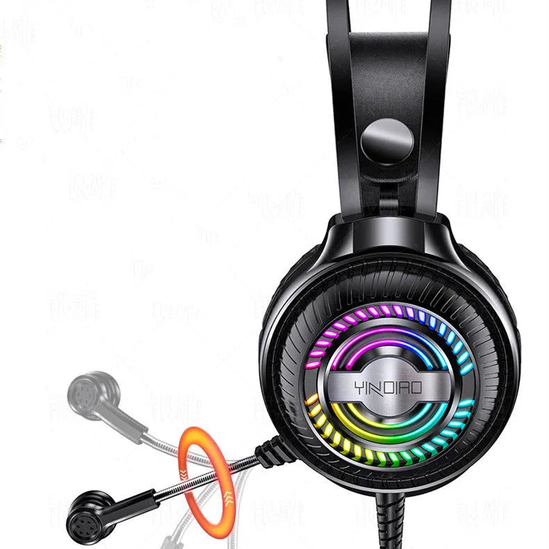 Black and white wired over-ear computer headset with microphone on a desk next to a laptop.