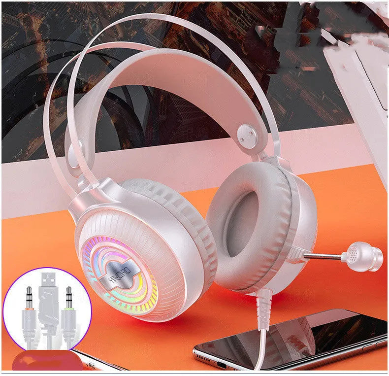 Black and white wired over-ear computer headset with microphone on a desk next to a laptop.