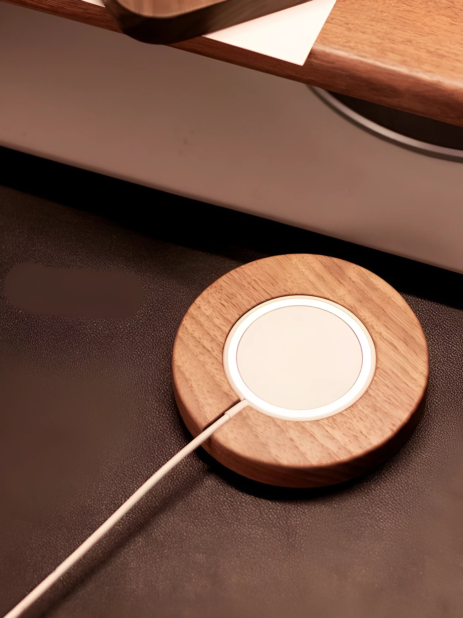 Walnut wood magnetic wireless charging base for MagSafe iPhones on a desk.