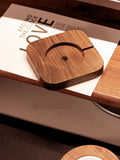 Walnut wood magnetic wireless charging base for MagSafe iPhones on a desk.