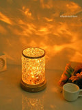 Rotating water ripple effect night light with acrylic body and solid wood base on a table.