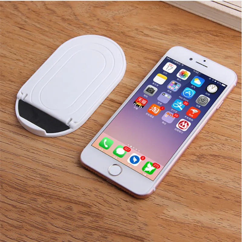 A plastic lazy bracket phone stand holding a mobile smartphone on a table.