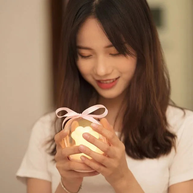 Pink cat paw shaped USB rechargeable night light with musical box function on wooden desktop