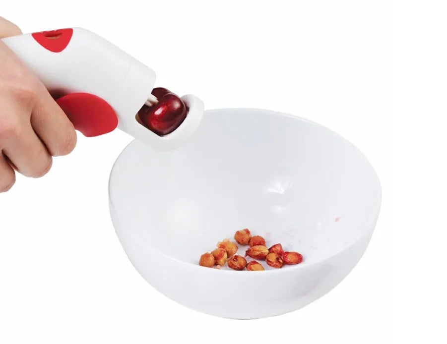 Stainless steel cherry kernel remover pitter tool on a kitchen worktop
